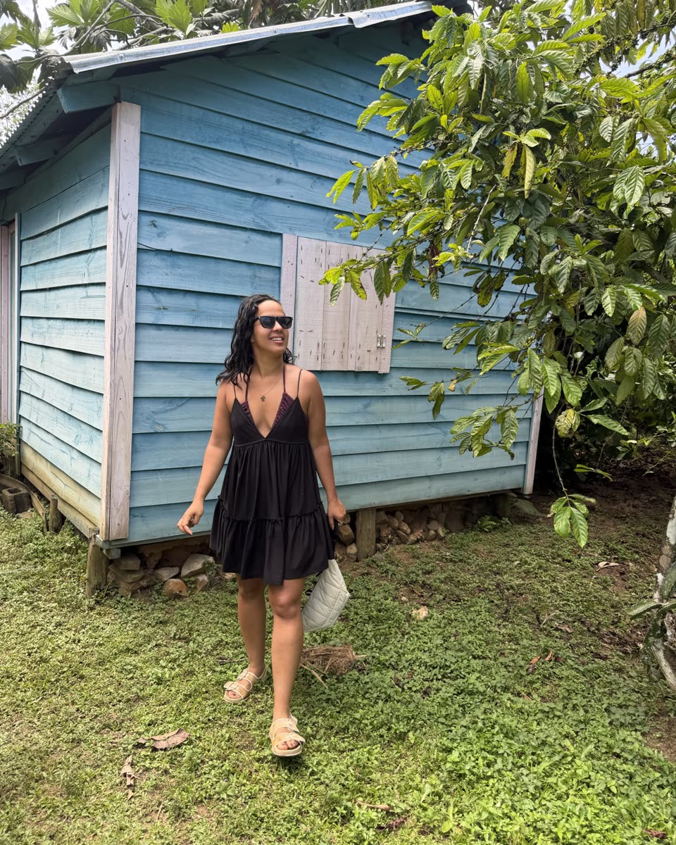 Indhira in front of a blue wooden house in the Dominican Republic